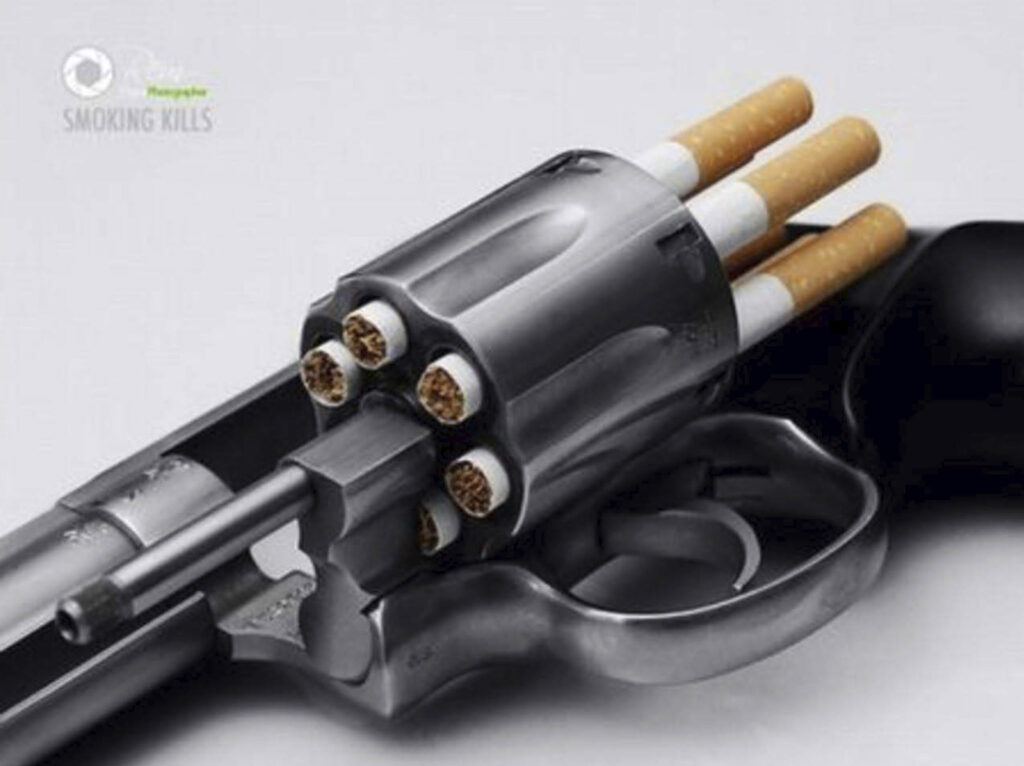 Anúncio publicitário. Texto: "Smoking kills". Foto de revolver com tambor à mostra e cigarros no lugar das balas.