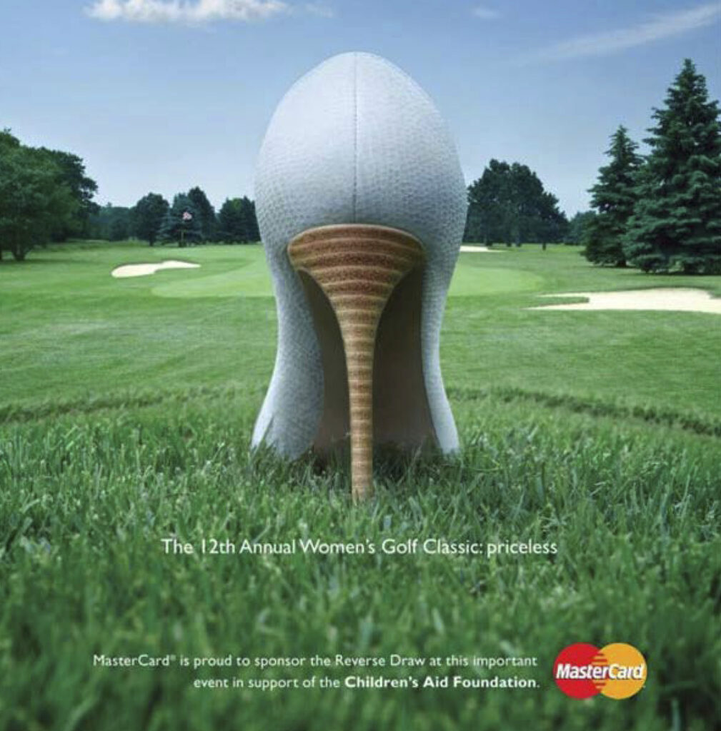 Anúncio publicitário MasterCard. Texto: "The 12th Annual Women's Golf Classic: priceless.". Imagem: Campo gramado de golf. Em primeiro plano, parte traseira de sapato de salto alto imitando um pino com bola de golf.