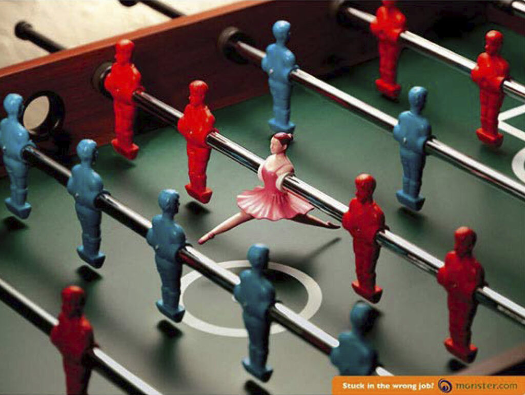 Anúncio publicitário Monster.com. Texto: "Stuck in the wrong job?". Foto de mesa de futebol de mesa com uma das peças substituída por uma bailarina.